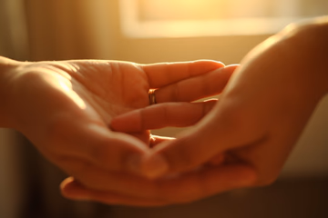 A warmly lit, blurred wide shot of intertwined hands symbolizing love and connection in Chambéry.