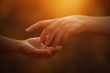 A warmly lit, blurred image of intertwined hands symbolizing reconnection and love, reflecting the theme of a successful 'retour affectif'.