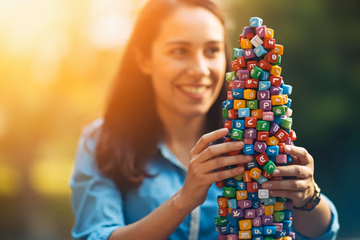 Person building a digital tower with social media icons, representing enhanced online presence through SMM panel.