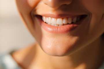 A bright, healthy smile representing the benefits of dental assessments, with a blurred background and warm lighting.